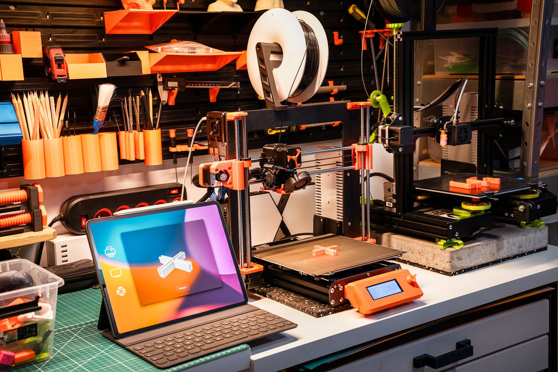 Completed 3D printed projects including phone stands and organizers in multiple colors on wood